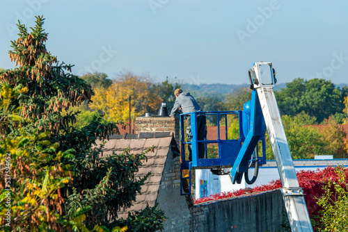 Furnace repairman repairing a chimney at a height while standing on a high-altitude lift