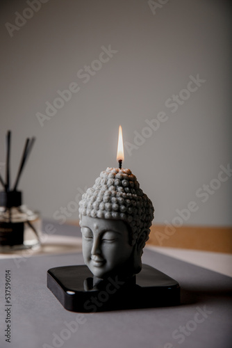 Statuette with candlestick. Statue of Buddha, incense sticks and burning candle. Aromatherapy, home fragrance. Concept of home relaxation and anti stress, zen buddhism.