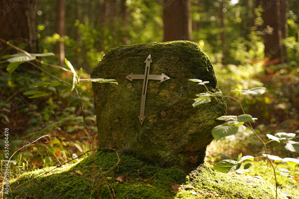 Iron Christian cross on a large stone in the forest Iron Christian cross on a large stone in the forest