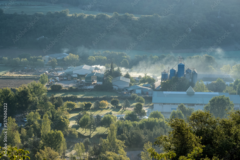 a farm and factory in a valley, steaming in the cold morning air, Pyrenees mountains, Spain