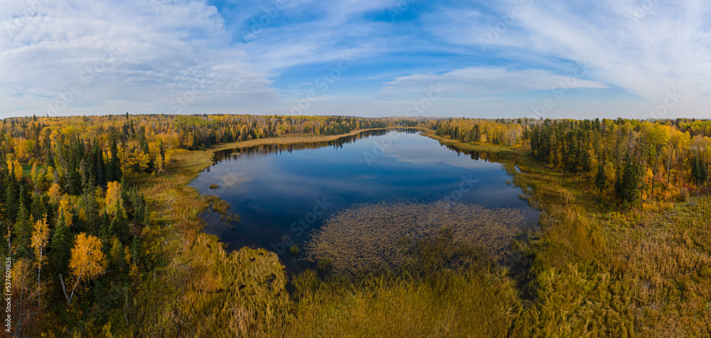Looking over a pond reflecting the clouds and surrounding brightly colored fall trees Looking over a pond reflecting the clouds and surrounding brightly colored fall trees