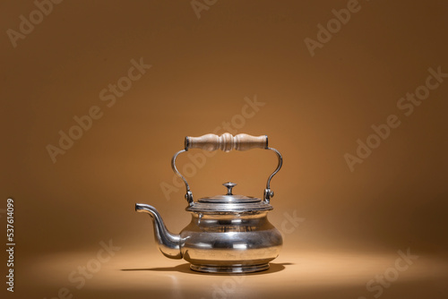 portrait of a metal teapot with a wooden handle, warm atmosphere