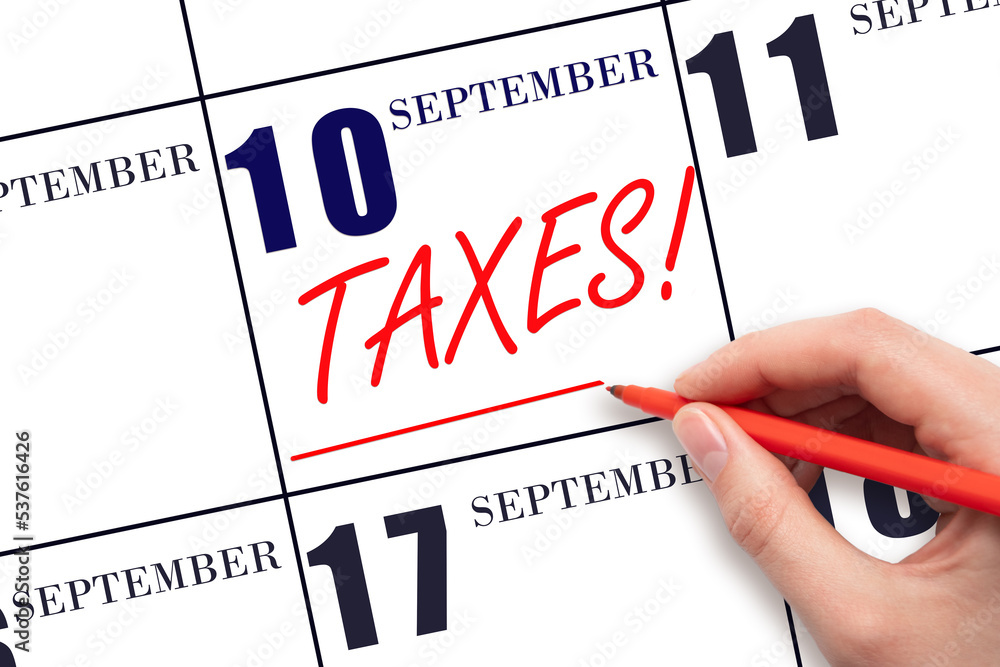 Hand drawing red line and writing the text Taxes on calendar date September 10. Remind date of tax payment Hand drawing red line and writing the text Taxes on calendar date September 10. Remind date of tax payment