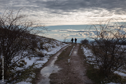 A distant couple on a mountain road, with snow at the sides