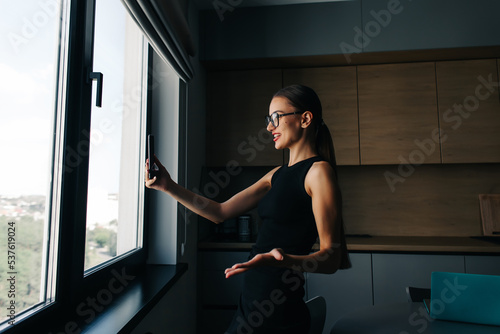 Fototapeta Naklejka Na Ścianę i Meble -  Серьезная очаровательная женщина, использующая смартфон во время работы