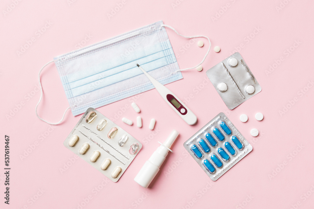 Protective face masks or surgical masks, medicine pills and thermometer on table background. Coronavirus disease. Corona virus concept. Space for text Protective face masks or surgical masks, medicine pills and thermometer on table background. Coronavirus disease. Corona virus concept. Space for text
