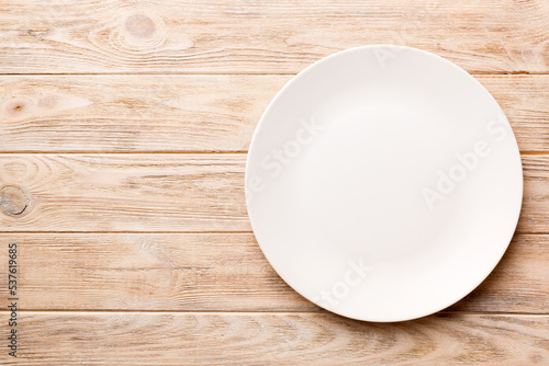 Top view of empty light plate on wooden background. Empty space for your design