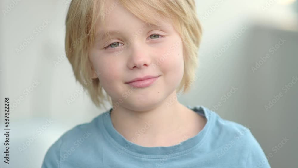 Slow motion close-up portrait of happy school-age child. Cute boy with blond hair emotionally laughs and looks at you. Real emotions of kids. Beautiful european child smiles and rejoices Slow motion close-up portrait of happy school-age child. Cute boy with blond hair emotionally laughs and looks at you. Real emotions of kids. Beautiful european child smiles and rejoices