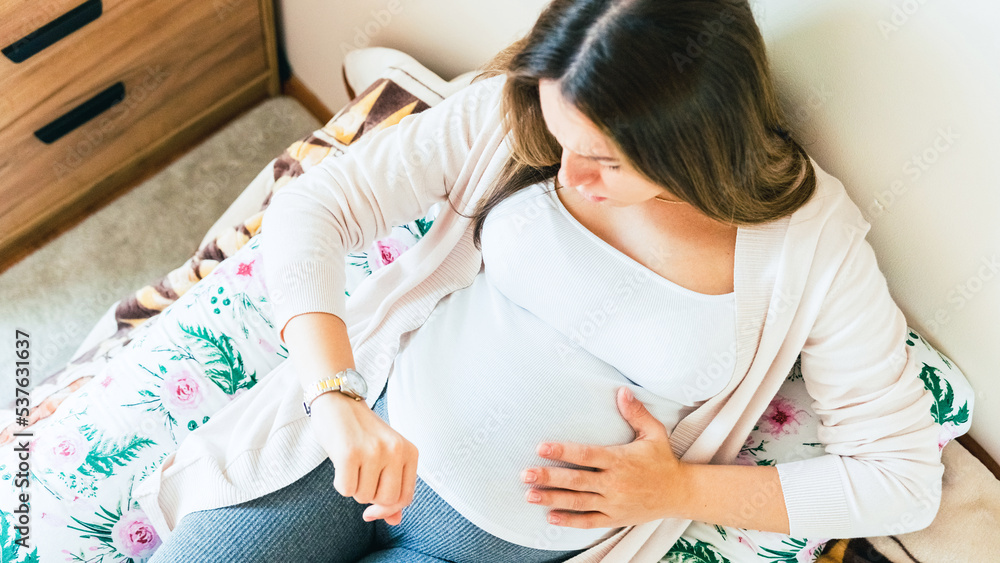 Pregnant clock time childbirth. Childbirth time, contractions pain. Pregnancy woman watching clock, holding baby belly. Pregnancy, medicine health care concept. Pregnant clock time childbirth. Childbirth time, contractions pain. Pregnancy woman watching clock, holding baby belly. Pregnancy, medicine health care concept.