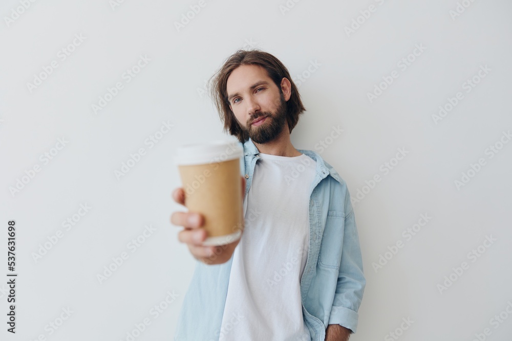 Freelance Millennial man with a beard drinking coffee from a recycled cup in stylish hipster clothes white T-shirt blue jeans and shirt on a white background Freelance Millennial man with a beard drinking coffee from a recycled cup in stylish hipster clothes white T-shirt blue jeans and shirt on a white background