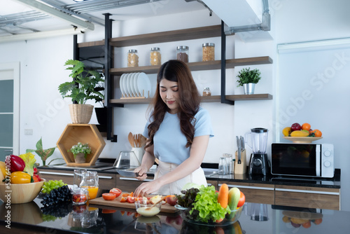 young asian woman cooking vegetable salad for breakfast in her home kitchen.