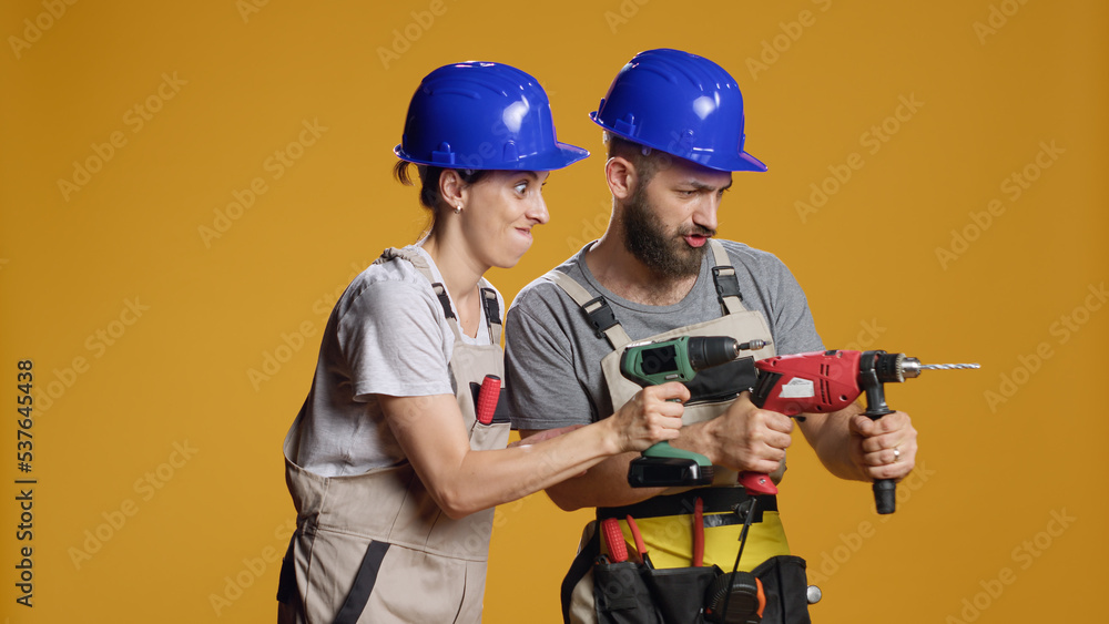 Team of contractors working with electric power drill machine to screw nails and plan construction rebuilding. Using drilling gun or nail gun to work on deconstruction and refurbishment.