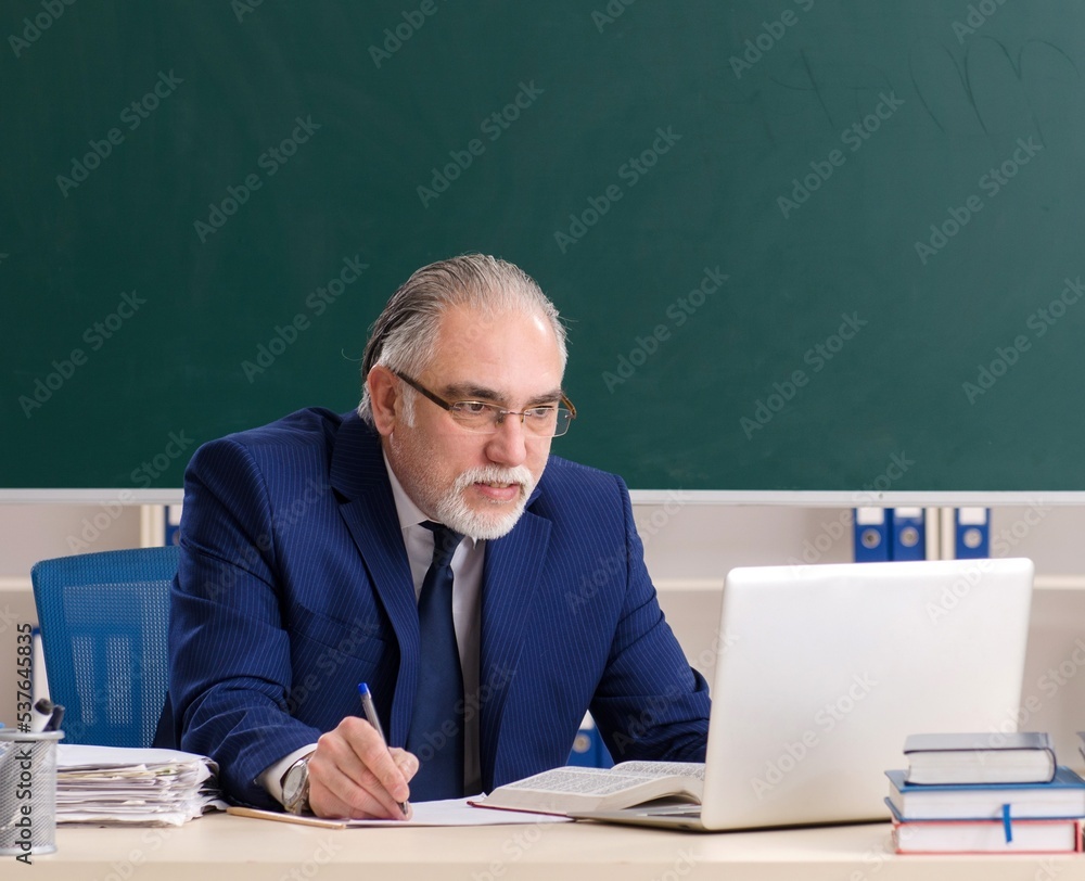 Aged male teacher in front of chalkboard Aged male teacher in front of chalkboard