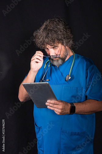 doctor dressed in the blue surgical suit consulting a tablet