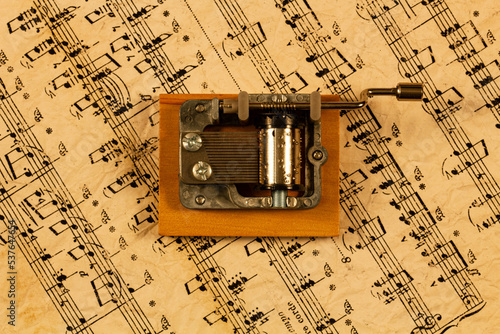 Music box and notes. Souvenir Music box on the background of old notes. Hand organ for classical and modern melody. Retro cylindrical mechanism with hand-cranked movements on wooden stand. Top view photo