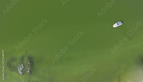A single boat on a green lake, photo from a drone, good background