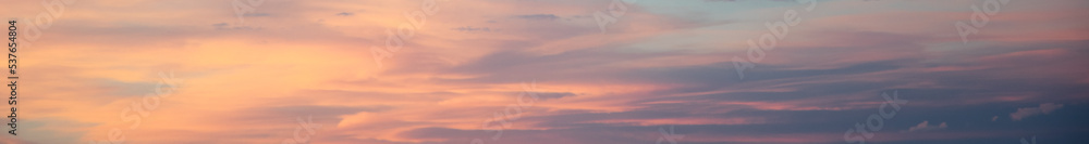Long horizontal abstract cloud banner. Bright orange and pink sunset sky. Copy space.