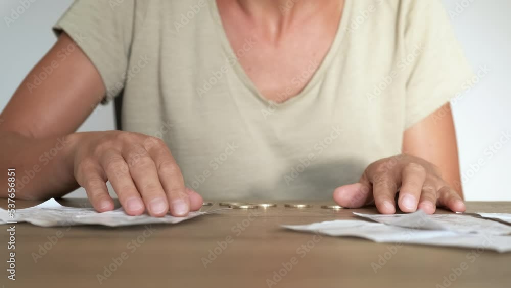 Check for energy price on table. A woman with coins on the table check the electricity bills in the room. Check for energy price on table. A woman with coins on the table check the electricity bills in the room.