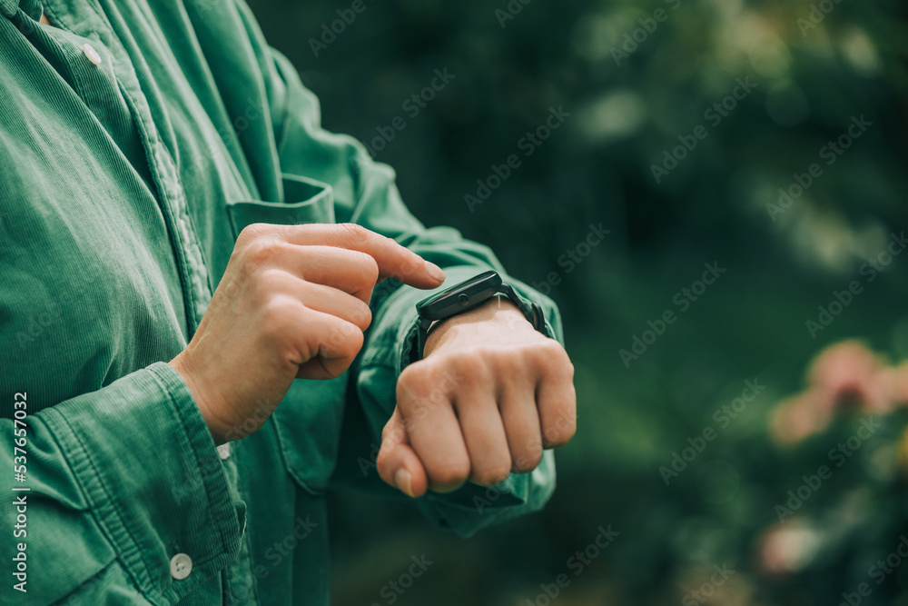 Stylish woman in green shirt check time and health indicators on wrist watch. Stylish woman in green shirt check time and health indicators on wrist watch.