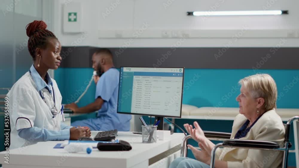 African american doctor doing checkup visit with female wheelchair user, talking about physical disability and healthcare diagnosis. Consulting woman with impairment at medical appointment. African american doctor doing checkup visit with female wheelchair user, talking about physical disability and healthcare diagnosis. Consulting woman with impairment at medical appointment.