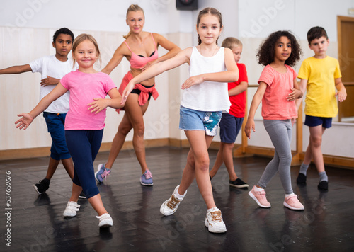 Smiling girls and boys doing dance workout during group class in fitness center