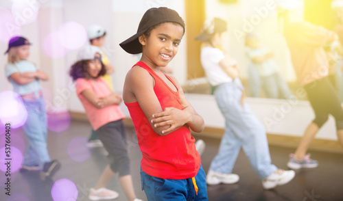 Portrait of confident tween african boy hip hop dancer posing during group dance class ..