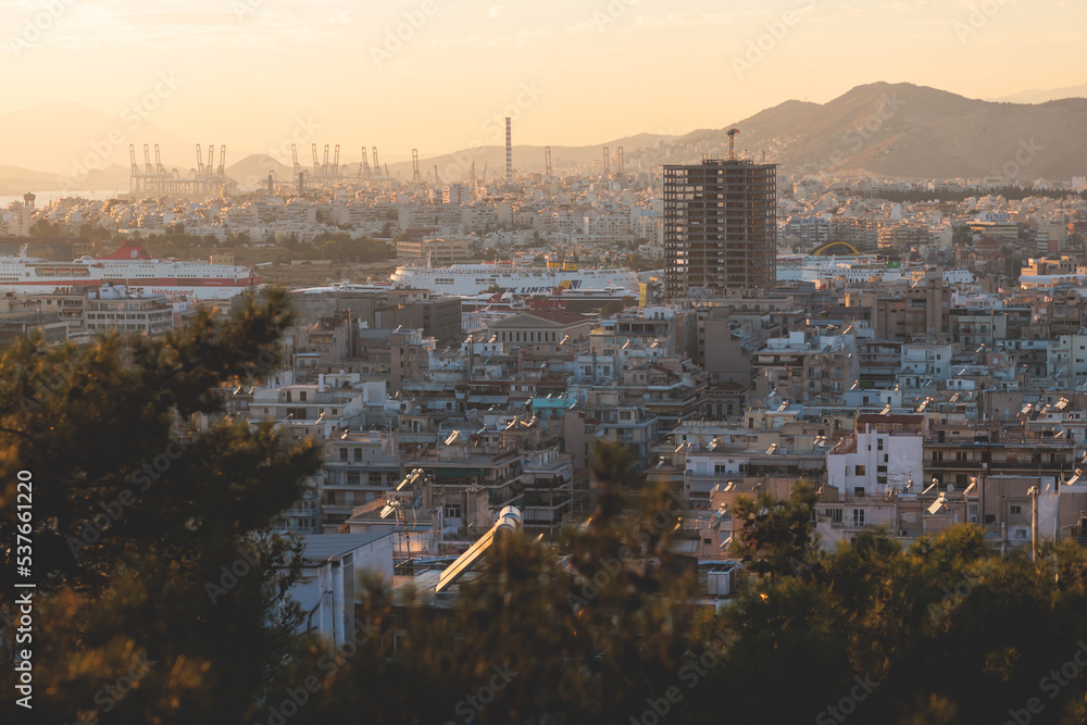 Obraz premium Piraeus city, Attica, beautiful panoramic view of Piraeus, Greece, with harbour and port, mountains and scenery beyond the city, seen from Prophet Helias Hill on Kastela Hill, sunset summer view