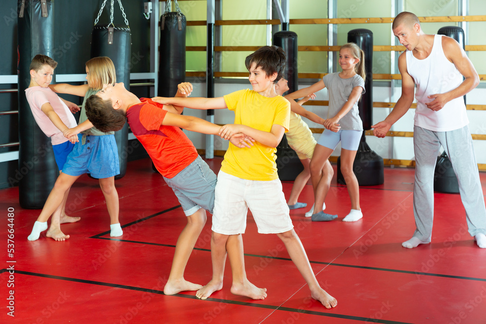 Kids in pairs training self-protection moves during their group training.