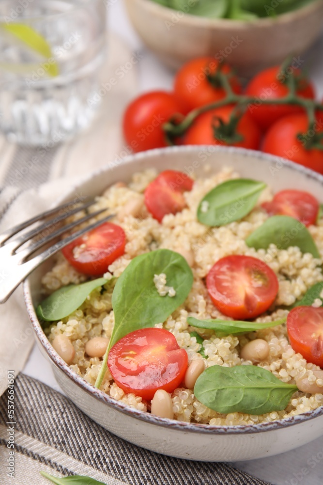 Delicious quinoa salad with tomatoes, beans and spinach leaves served on table, closeup Delicious quinoa salad with tomatoes, beans and spinach leaves served on table, closeup