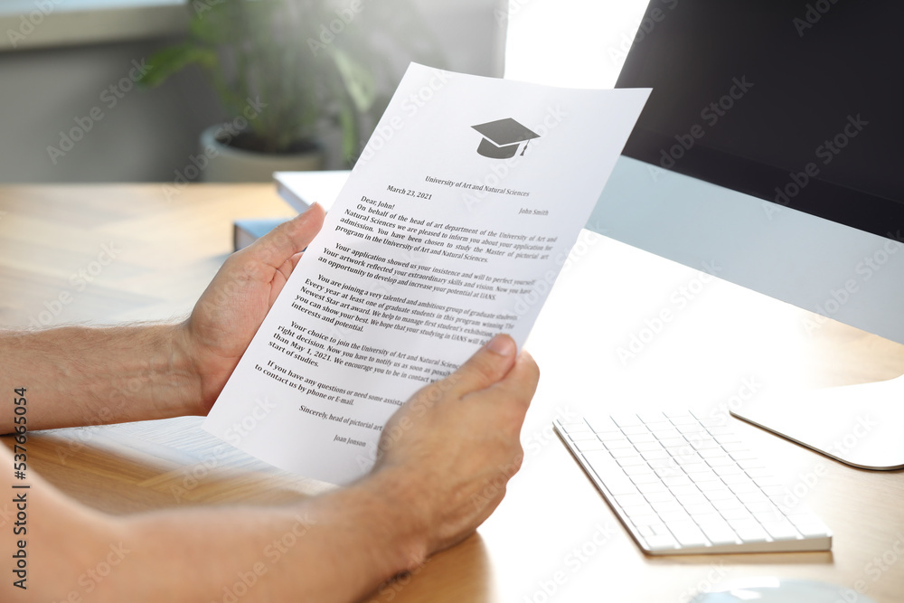 Obraz premium Student with acceptance letter from university at wooden table indoors, closeup