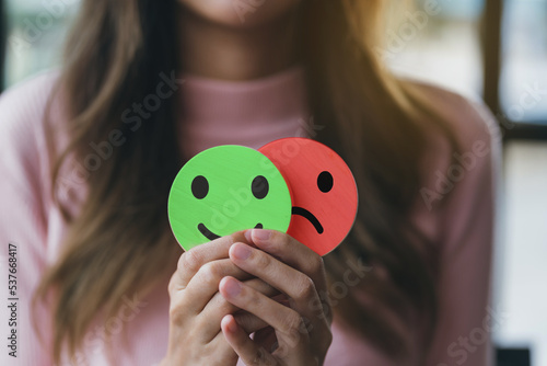 Print op canvas Woman Hands holding sad face hiding or behind happy smiley face, bipolar and depression, mental health concept, personality, mood change, therapy healing split concept