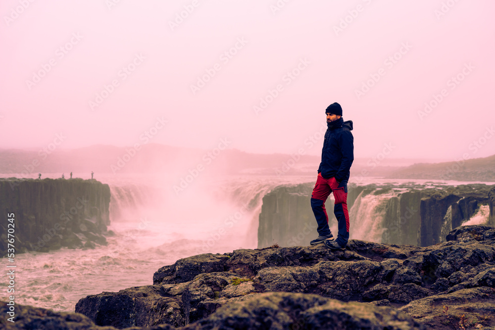 portrait of sporty man on rock among impressive waterfalls in the arctic polar circle in autumn winter