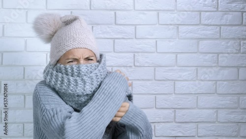 Heating crisis in female cold room. A female suffer from heating crisis and stay in the cold flat wrapped in woollen scarf.