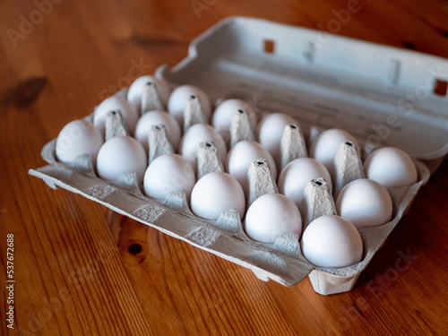 White raw chicken eggs in egg cardboard box photo