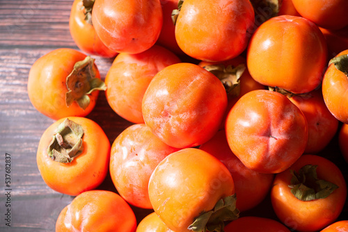 Fotografie Ripe persimmon or kaki fruit on wooden table.
