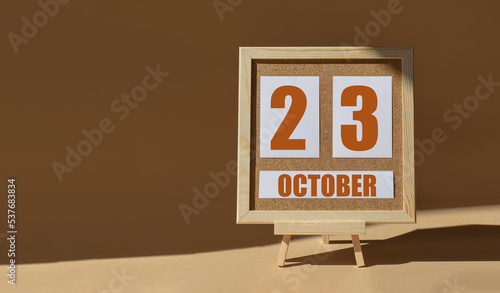 October 23th. Day 23 of month, Calendar date. Cork board, easel in sunlight on desktop. Close-up, brown background. Autumn month, day of year concept photo