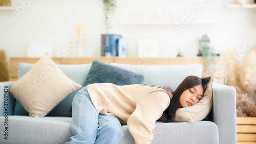 Asian woman resting at home on couch, feeling exhausted after work, lacking energy, or overworked, too tired, and lacking motivation photo