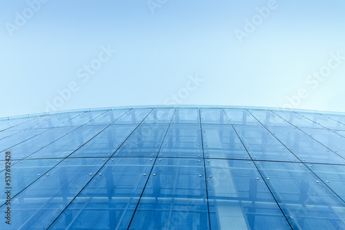 transparent glass wall of office building against clear blue sky. abstract urban background.