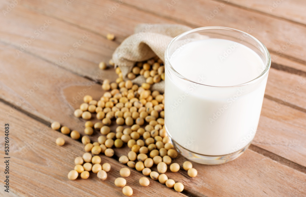 Soy milk in a glass with soybeans on a wooden table organic drink high protein healthy breakfast agricultural produce vegetarian - top view Soy milk in a glass with soybeans on a wooden table organic drink high protein healthy breakfast agricultural produce vegetarian - top view
