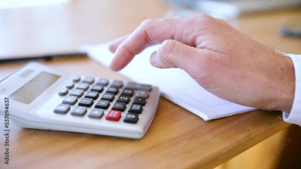 A person's hand typing into a calculator. A person's hand typing into a calculator.