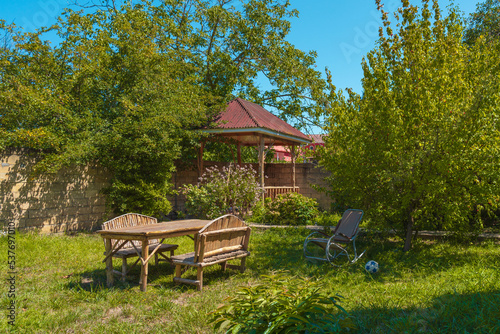 Wooden handmade table and benches on the grass in the garden of country house