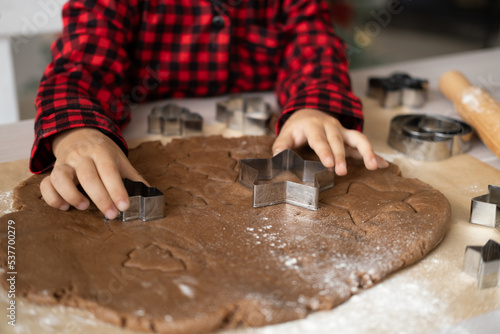 little kid girl in red pajama cooking festive gingerbread in christmas decorated kitchen. christmas cookies