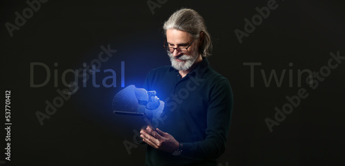 Senior businessman with tablet computer and his digital projection on dark background. Concept of digital twin photo