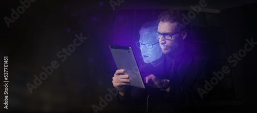 Young businessman with tablet computer and his digital projection on dark background. Concept of digital twin