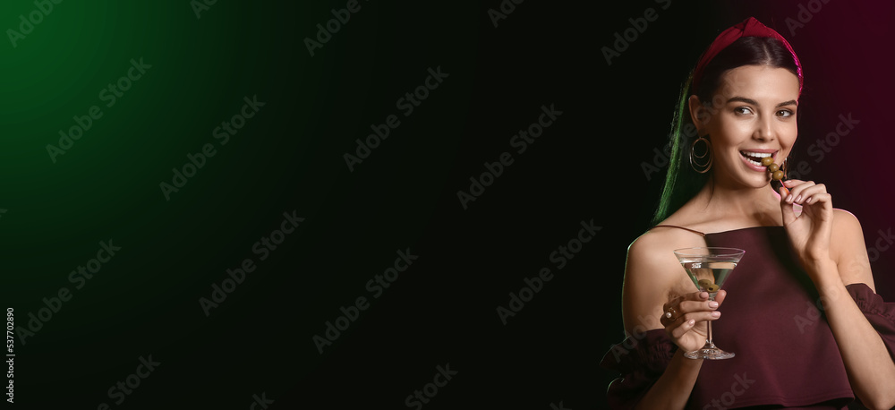 Beautiful young woman drinking martini with olives on dark background with space for text Beautiful young woman drinking martini with olives on dark background with space for text