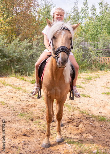 Outside on a beautiful warm day, a girl rides a horse.