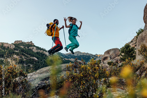 Couple jumping of rock at mountain