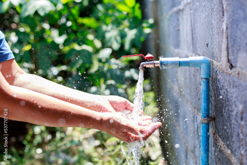 aucet with water droplets Falling into the hand