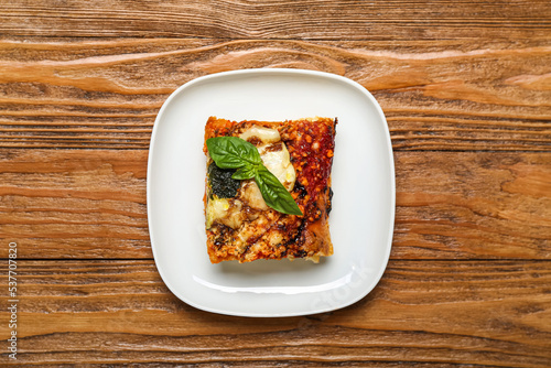Plate with tasty Italian pie with mozzarella and pesto sauce on wooden background