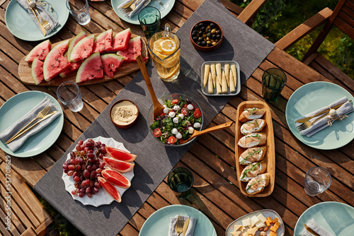Top view image of wooden dinner table set for Summer party outdoors with fresh fruits and berries